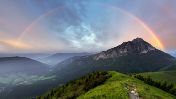 Arcoiris en el fondo de un paisaje de montañas verdes