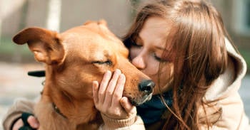 chica besando a su perro en la calle