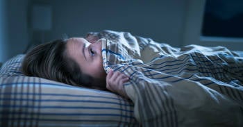 como evitar tener pesadillas noche mujer despierta asustada por una pesadilla en la noche.
