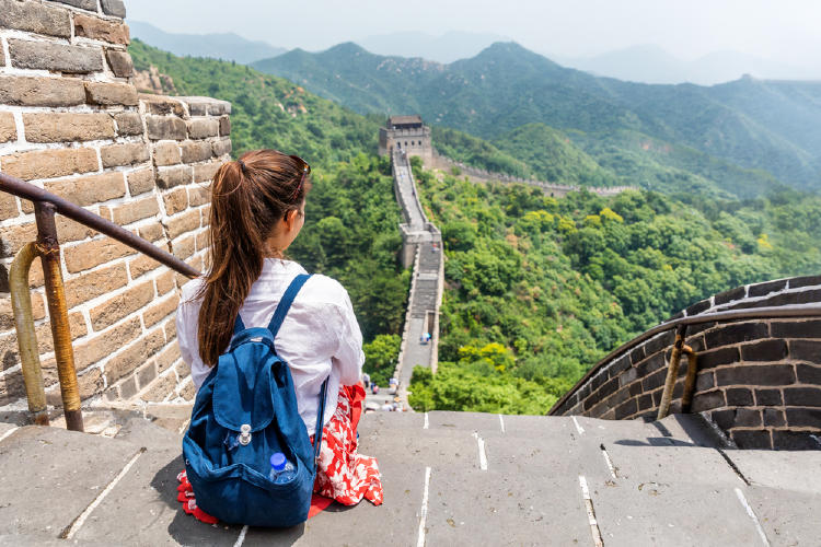 mujer sentada en la muralla china viendo hacia ella sin turistas