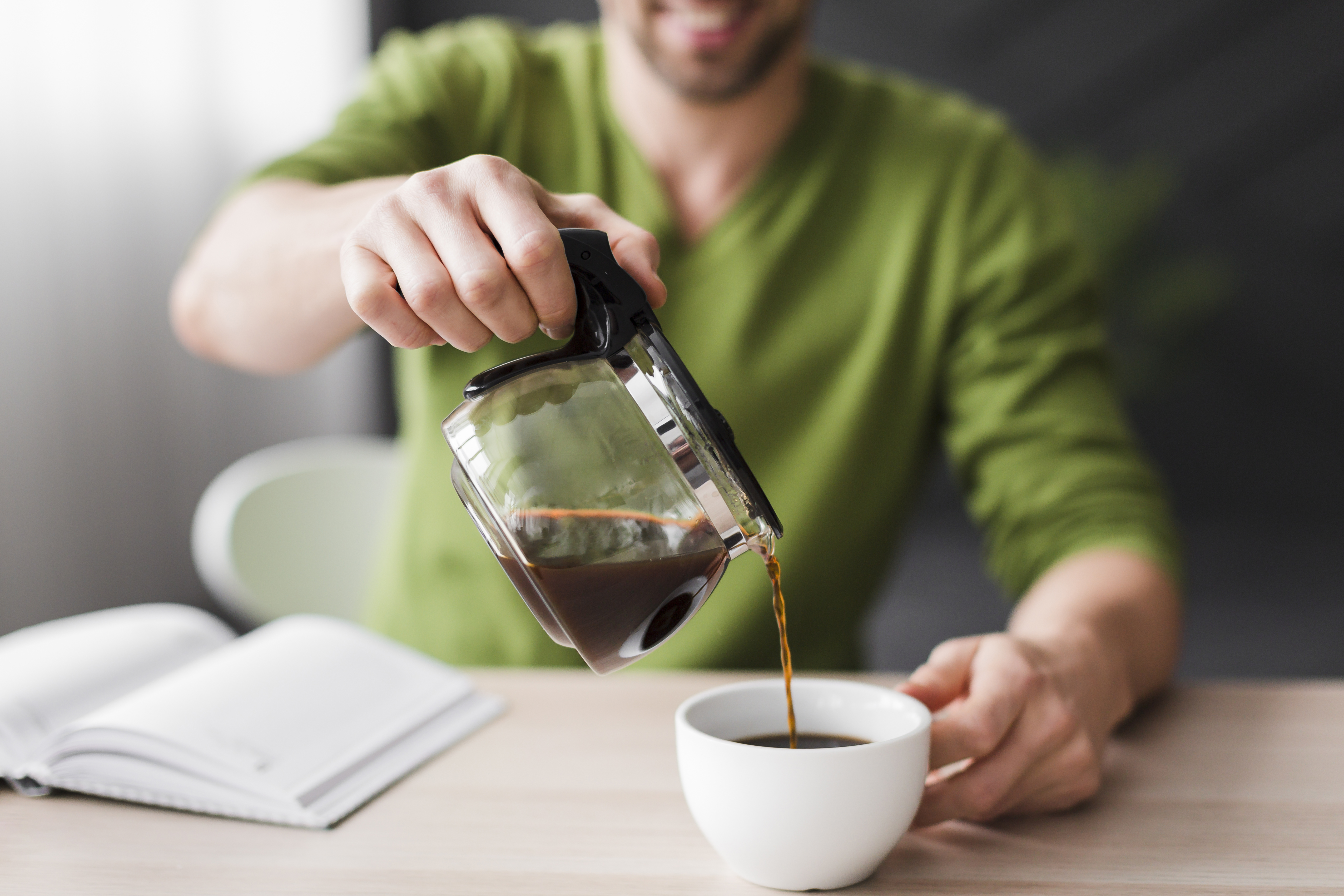 man green shirt pouring coffee close up