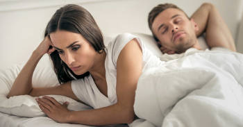 mujer enojada con su pareja en la cama
